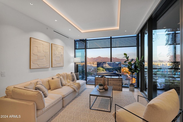 living room with a tray ceiling, a wealth of natural light, and a wall of windows