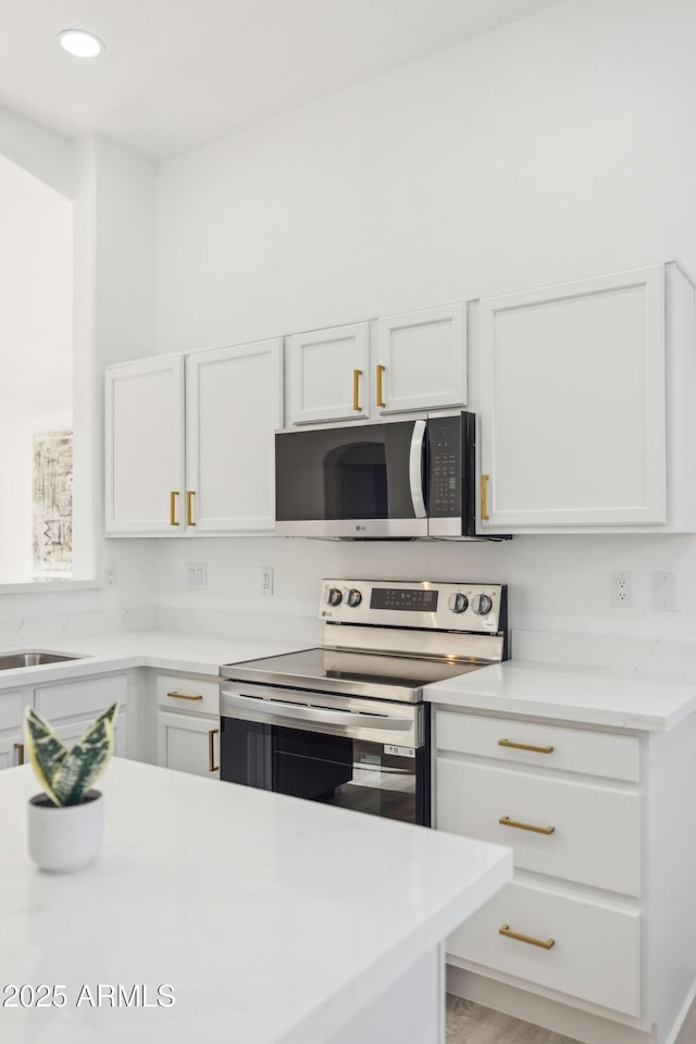 kitchen featuring a sink, light countertops, stainless steel appliances, recessed lighting, and white cabinetry