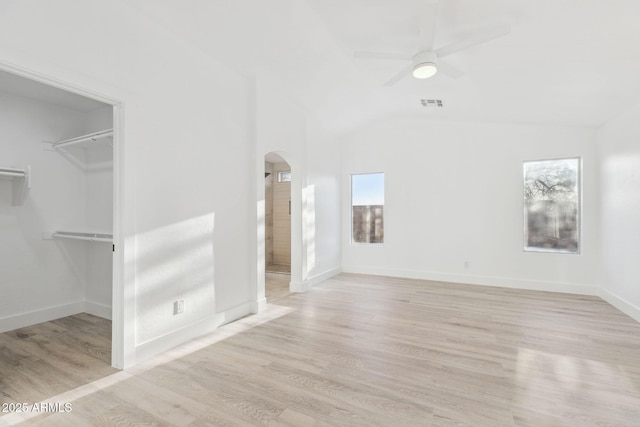 unfurnished living room with visible vents, light wood-style floors, ceiling fan, arched walkways, and vaulted ceiling