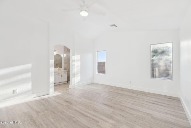 spare room featuring arched walkways, a ceiling fan, vaulted ceiling, light wood-type flooring, and visible vents