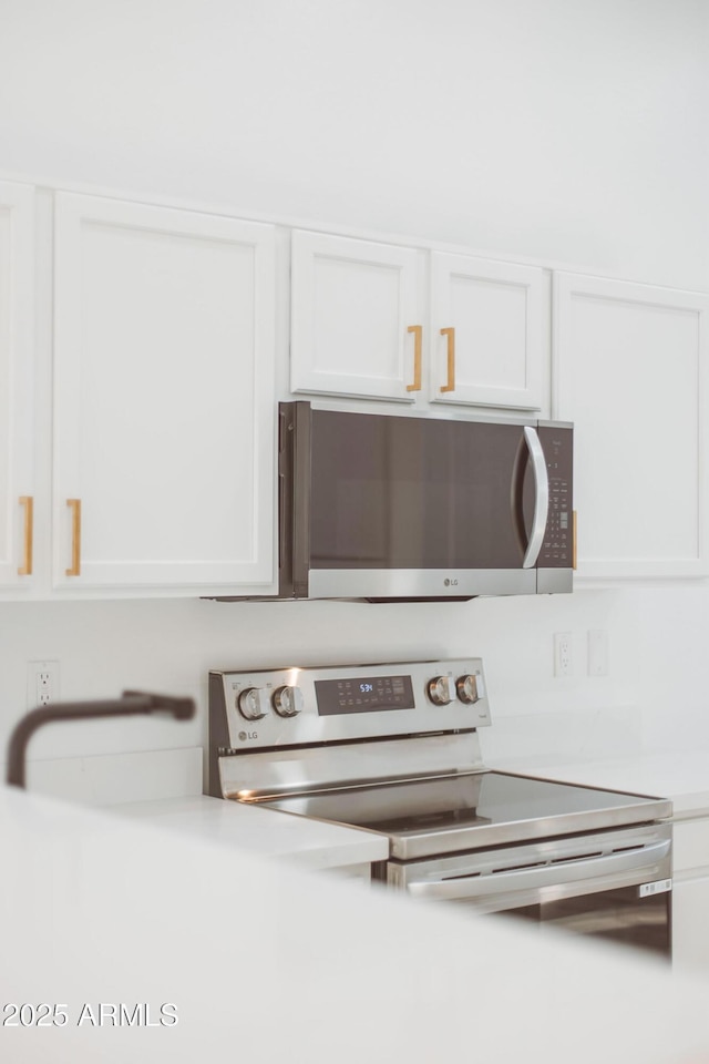 room details featuring light countertops, white cabinets, and stainless steel appliances