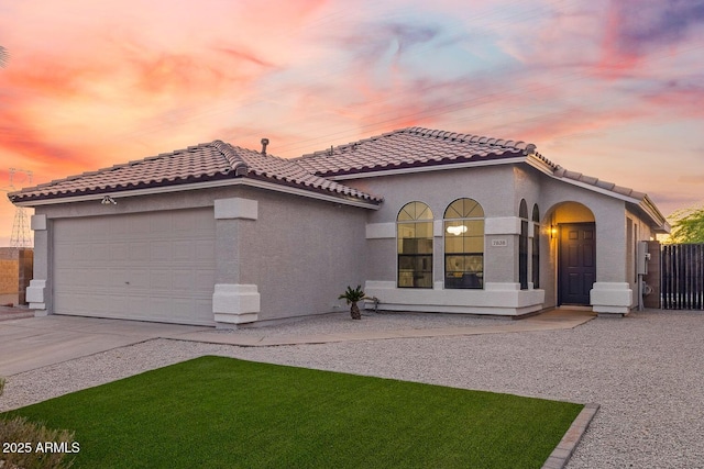 mediterranean / spanish-style house with driveway, a tile roof, a garage, fence, and stucco siding