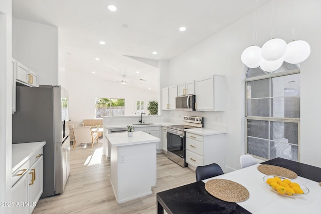 kitchen with appliances with stainless steel finishes, light countertops, recessed lighting, a peninsula, and light wood-type flooring