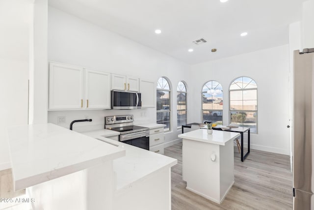 kitchen featuring plenty of natural light, a kitchen island, stainless steel appliances, and visible vents