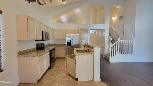 kitchen featuring a center island with sink, visible vents, appliances with stainless steel finishes, a sink, and light stone countertops