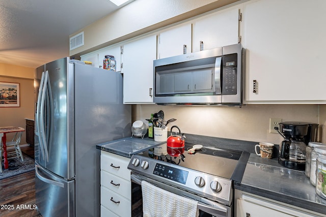 kitchen featuring stainless steel appliances, white cabinetry, and dark wood-type flooring