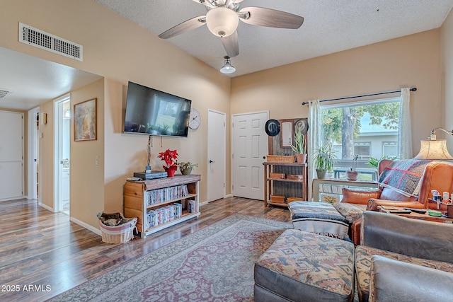 living room with ceiling fan, wood-type flooring, and a textured ceiling