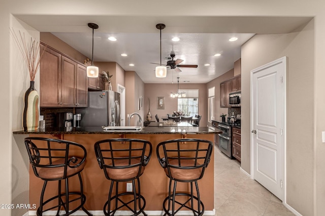 kitchen featuring tasteful backsplash, a breakfast bar, kitchen peninsula, and appliances with stainless steel finishes