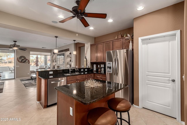 kitchen with a breakfast bar, dark stone counters, hanging light fixtures, kitchen peninsula, and stainless steel appliances