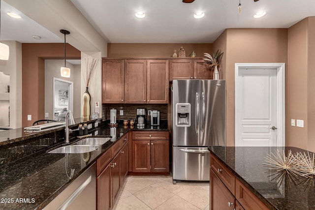 kitchen featuring pendant lighting, sink, appliances with stainless steel finishes, backsplash, and dark stone counters