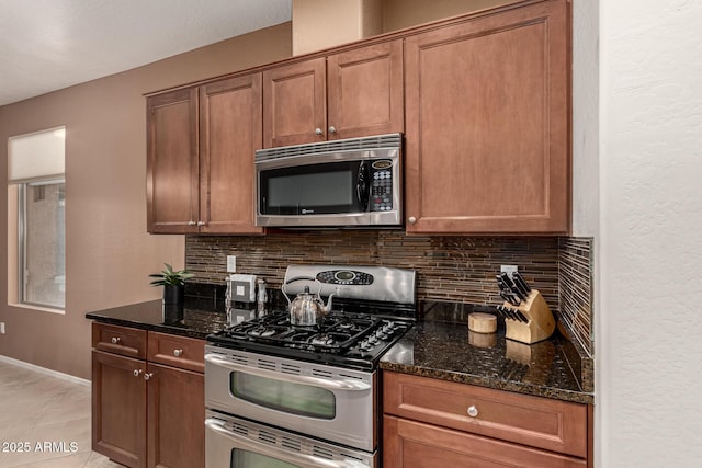 kitchen with tasteful backsplash, appliances with stainless steel finishes, and dark stone countertops