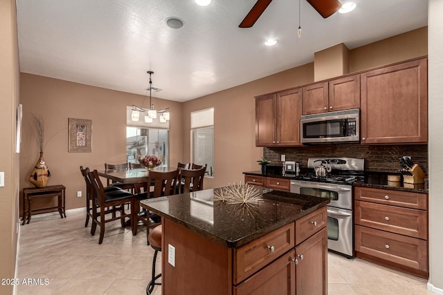 kitchen featuring a center island, hanging light fixtures, dark stone counters, stainless steel appliances, and decorative backsplash