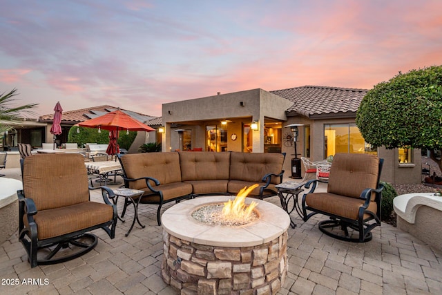 patio terrace at dusk with an outdoor living space with a fire pit