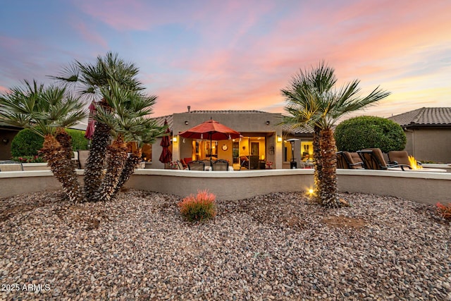 back house at dusk with a fire pit and a patio