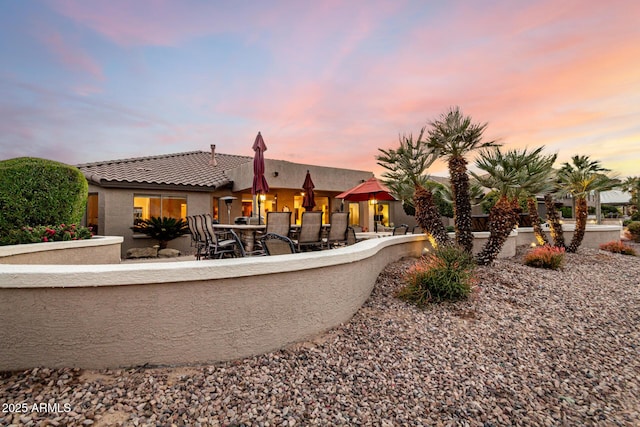 back house at dusk with a patio area