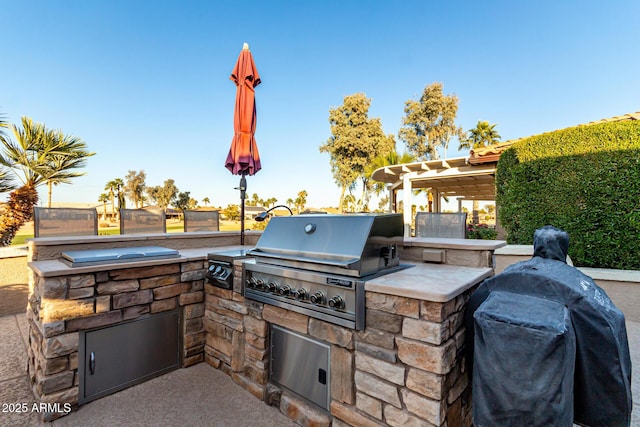 view of patio / terrace featuring exterior kitchen, grilling area, and a pergola