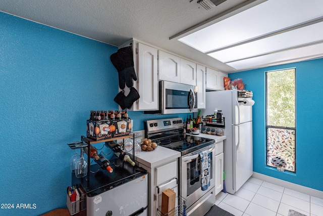 kitchen featuring light tile patterned flooring, appliances with stainless steel finishes, a textured ceiling, and white cabinetry