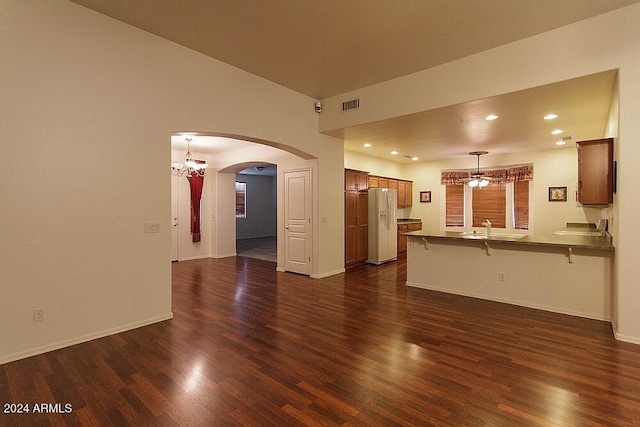 unfurnished living room featuring dark hardwood / wood-style floors, a notable chandelier, and sink