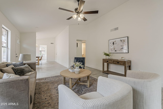 living room featuring light wood-type flooring, visible vents, high vaulted ceiling, baseboards, and ceiling fan