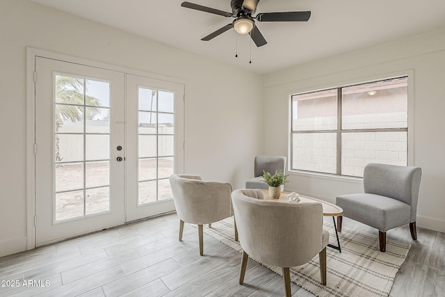 living area featuring light wood finished floors, french doors, baseboards, and ceiling fan