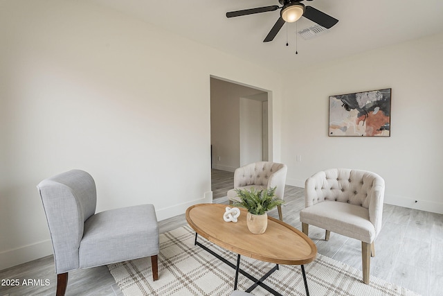 sitting room with ceiling fan, visible vents, baseboards, and light wood-style flooring