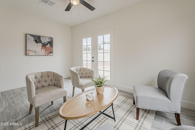 living area featuring visible vents, baseboards, ceiling fan, and wood finished floors