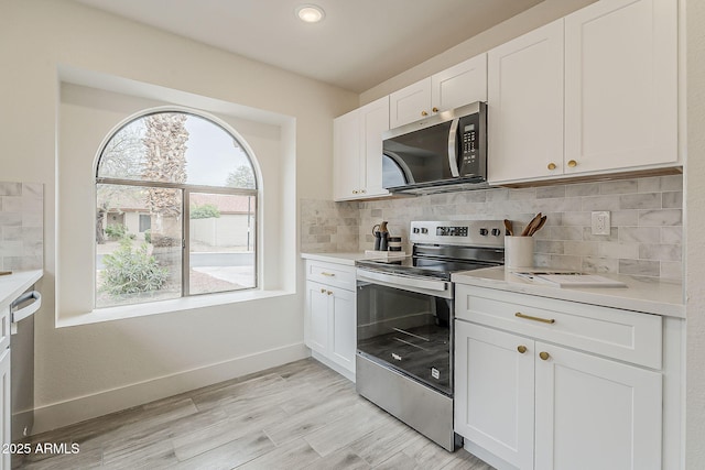 kitchen with baseboards, stainless steel appliances, decorative backsplash, light countertops, and white cabinets