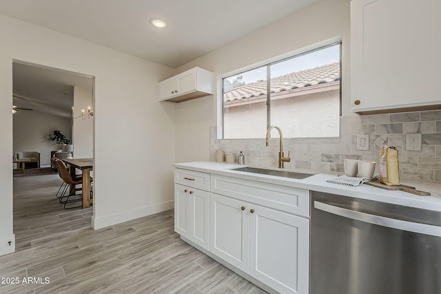 kitchen with a sink, tasteful backsplash, light wood-style floors, light countertops, and dishwasher