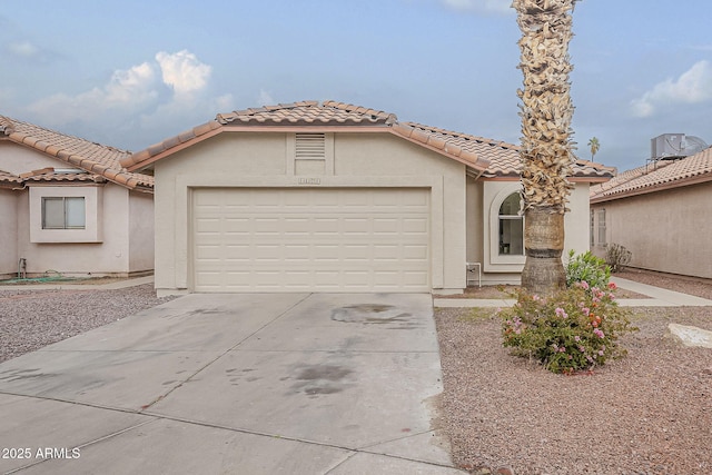 mediterranean / spanish-style house featuring a tile roof, concrete driveway, a garage, and stucco siding