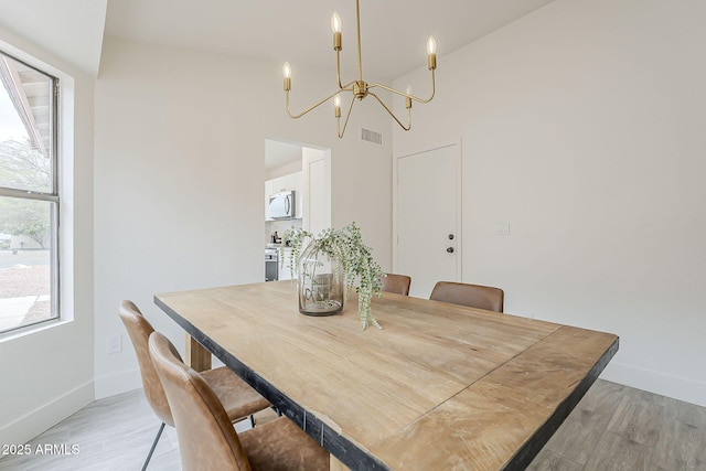 dining space with a chandelier, visible vents, light wood-style floors, and baseboards