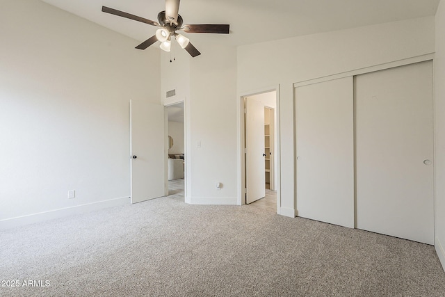 unfurnished bedroom with visible vents, baseboards, light colored carpet, a closet, and high vaulted ceiling