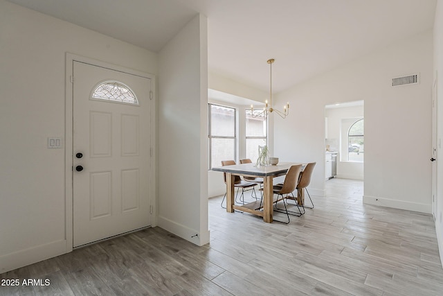 foyer featuring light wood-style floors, visible vents, lofted ceiling, and an inviting chandelier