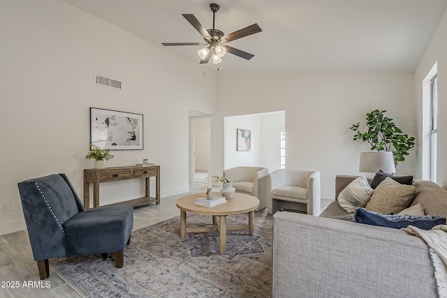 living area featuring visible vents, baseboards, a ceiling fan, and wood finished floors