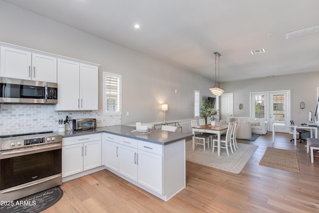 4438 N 27th St Unit 27, Phoenix, AZ 85016 - kitchen with stainless steel appliances, white cabinetry, backsplash, a peninsula, and dark countertops