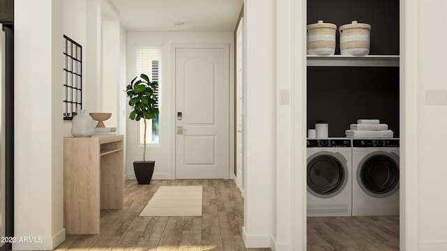 clothes washing area featuring washer and clothes dryer, laundry area, and wood finished floors