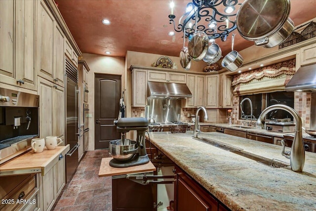 7710 E Golden Eagle Cir, Gold Canyon, AZ 85118 - kitchen with under cabinet range hood, stone tile floors, a sink, decorative backsplash, and light stone counters