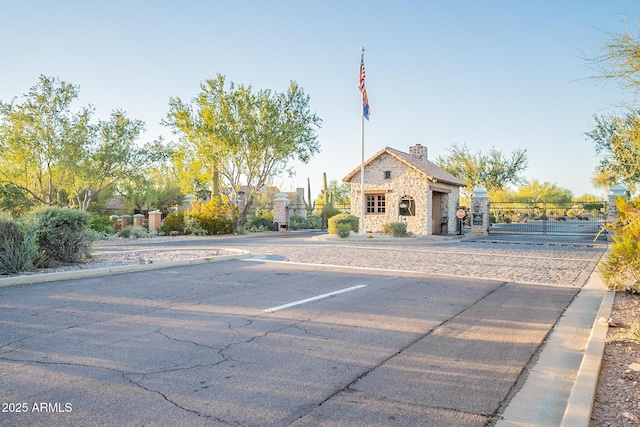 7710 E Golden Eagle Cir, Gold Canyon, AZ 85118 - view of front of home featuring stone siding, a gate, uncovered parking, a chimney, and an outbuilding