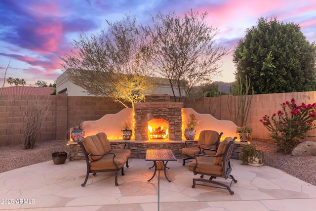 3733 E Kachina Dr, Phoenix, AZ 85044 - patio terrace at dusk featuring an outdoor stone fireplace, a fenced backyard, and a patio area