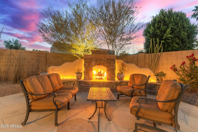3733 E Kachina Dr, Phoenix, AZ 85044 - patio terrace at dusk with an outdoor living space with a fireplace, a fenced backyard, and a patio