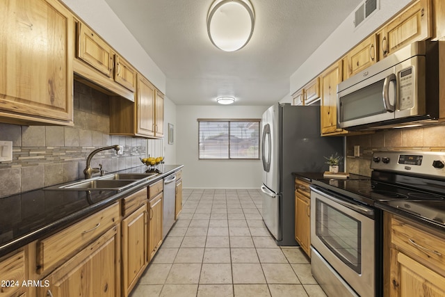 kitchen featuring tasteful backsplash, sink, light tile patterned floors, and stainless steel appliances