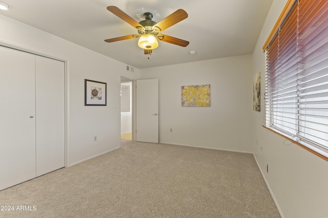 unfurnished bedroom featuring ceiling fan, a closet, and light colored carpet