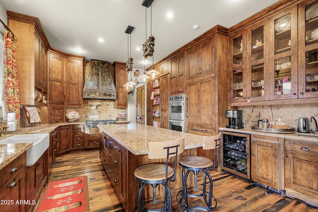 51238 N Pinal Ranch Rd, Miami, AZ 85539 - kitchen featuring wine cooler, a center island, brown cabinetry, stainless steel double oven, and a sink