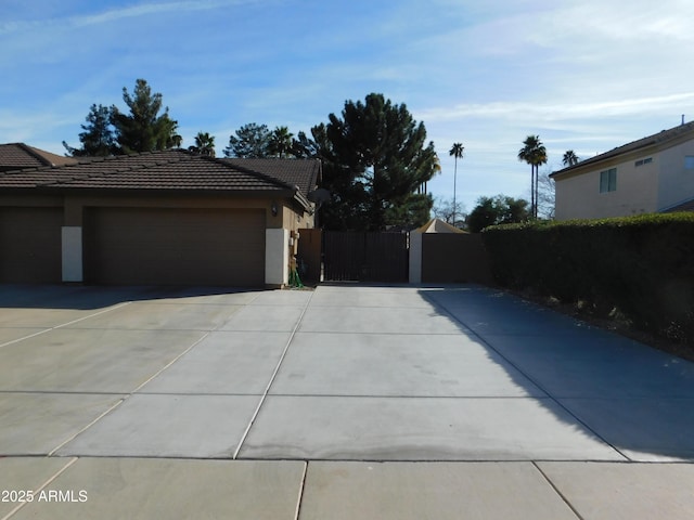 exterior space with a garage, concrete driveway, a tile roof, fence, and stucco siding