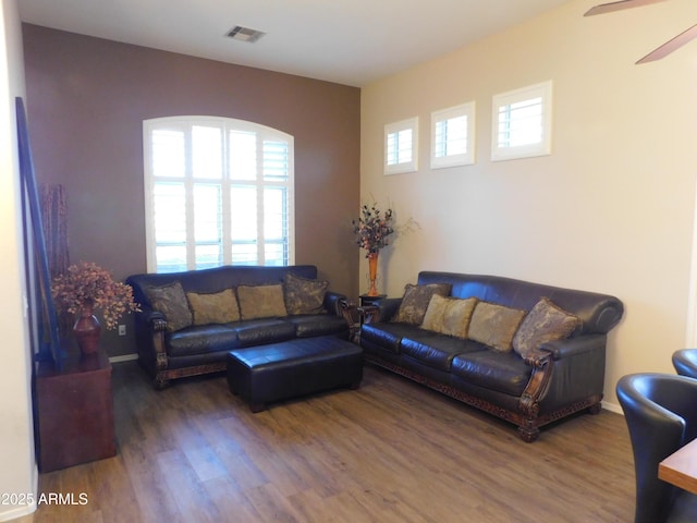 living area with baseboards, wood finished floors, visible vents, and a ceiling fan