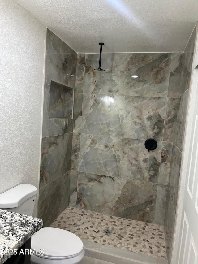 bathroom featuring vanity, tiled shower, and toilet