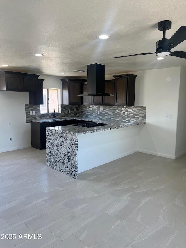 kitchen featuring black gas cooktop, tasteful backsplash, light stone countertops, island exhaust hood, and kitchen peninsula