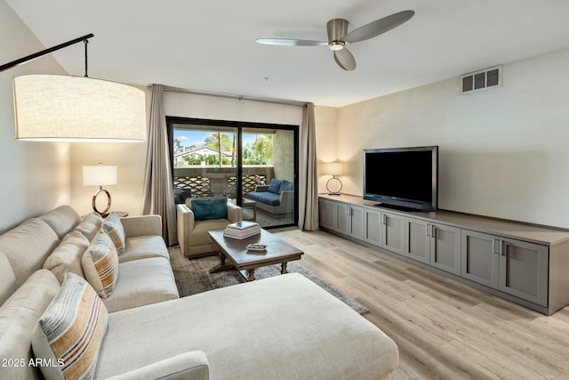living room with light wood finished floors, ceiling fan, and visible vents