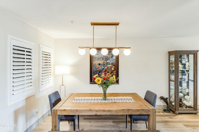 dining space with baseboards and light wood-type flooring