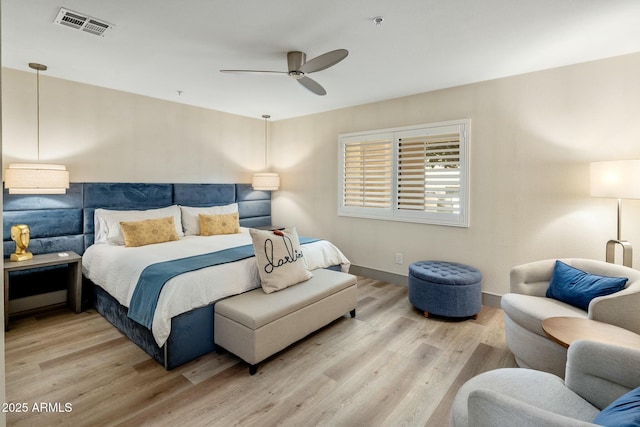 bedroom featuring visible vents, baseboards, ceiling fan, and wood finished floors