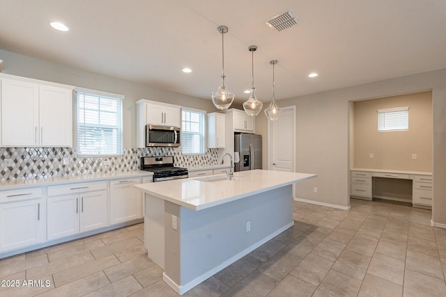 613 W Winchester Dr, Chandler, AZ 85286 - kitchen featuring stainless steel appliances, a sink, backsplash, a kitchen island with sink, and light countertops
